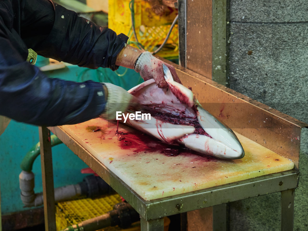 Cropped hands of butcher cutting fish at market