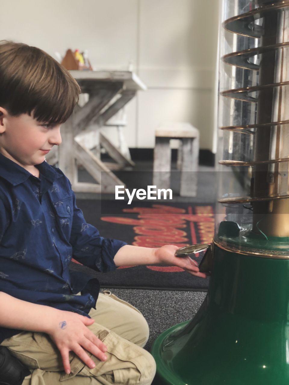 Boy looking at equipment while kneeling at cafe