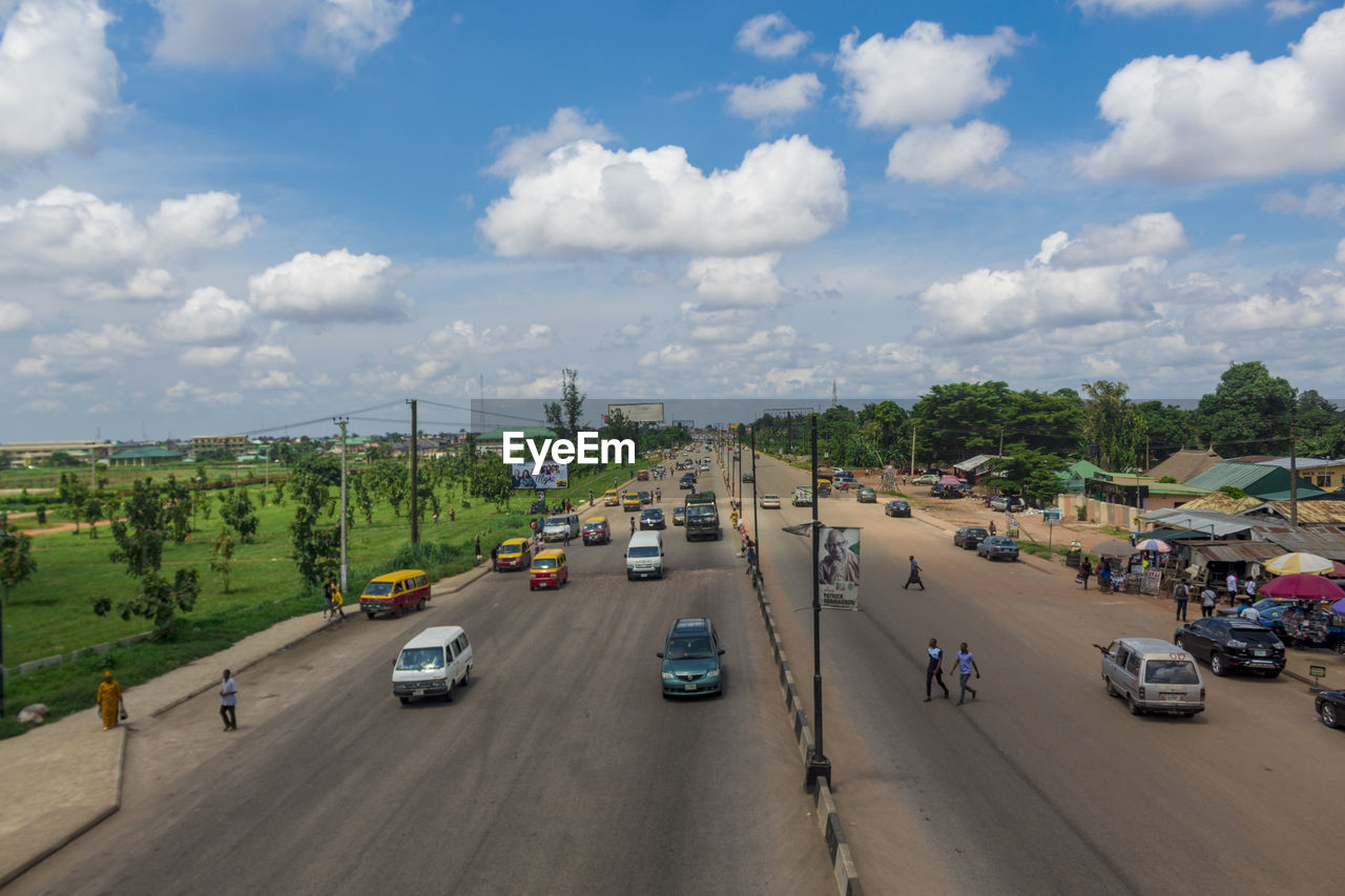 HIGH ANGLE VIEW OF CARS ON ROAD IN CITY AGAINST SKY