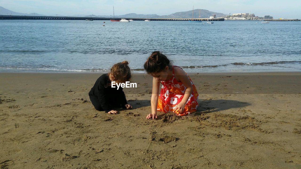 Sisters playing on sand at beach