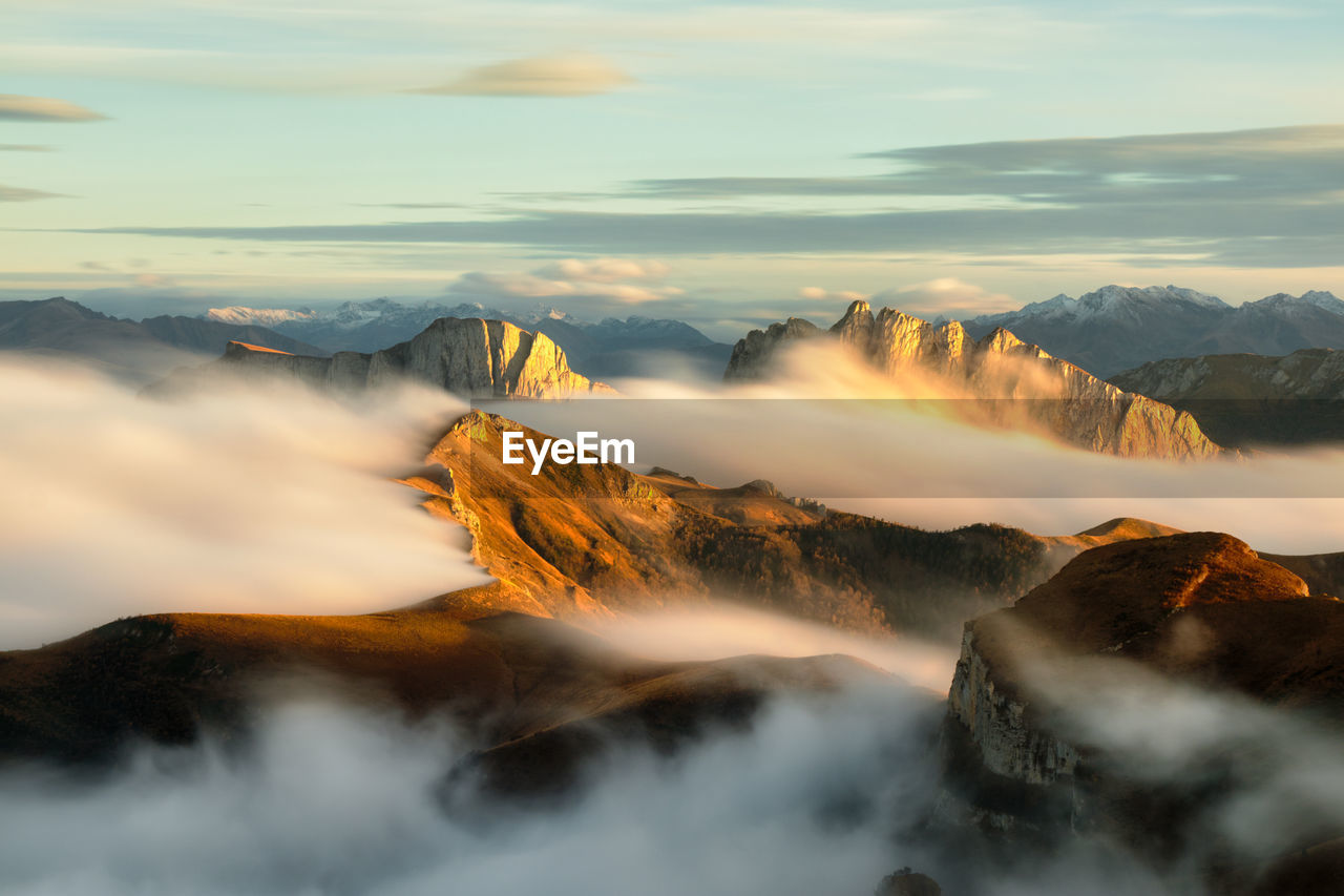 Mountains in fog at sunset in autumn. landscape with alpine mountain valley, low clouds