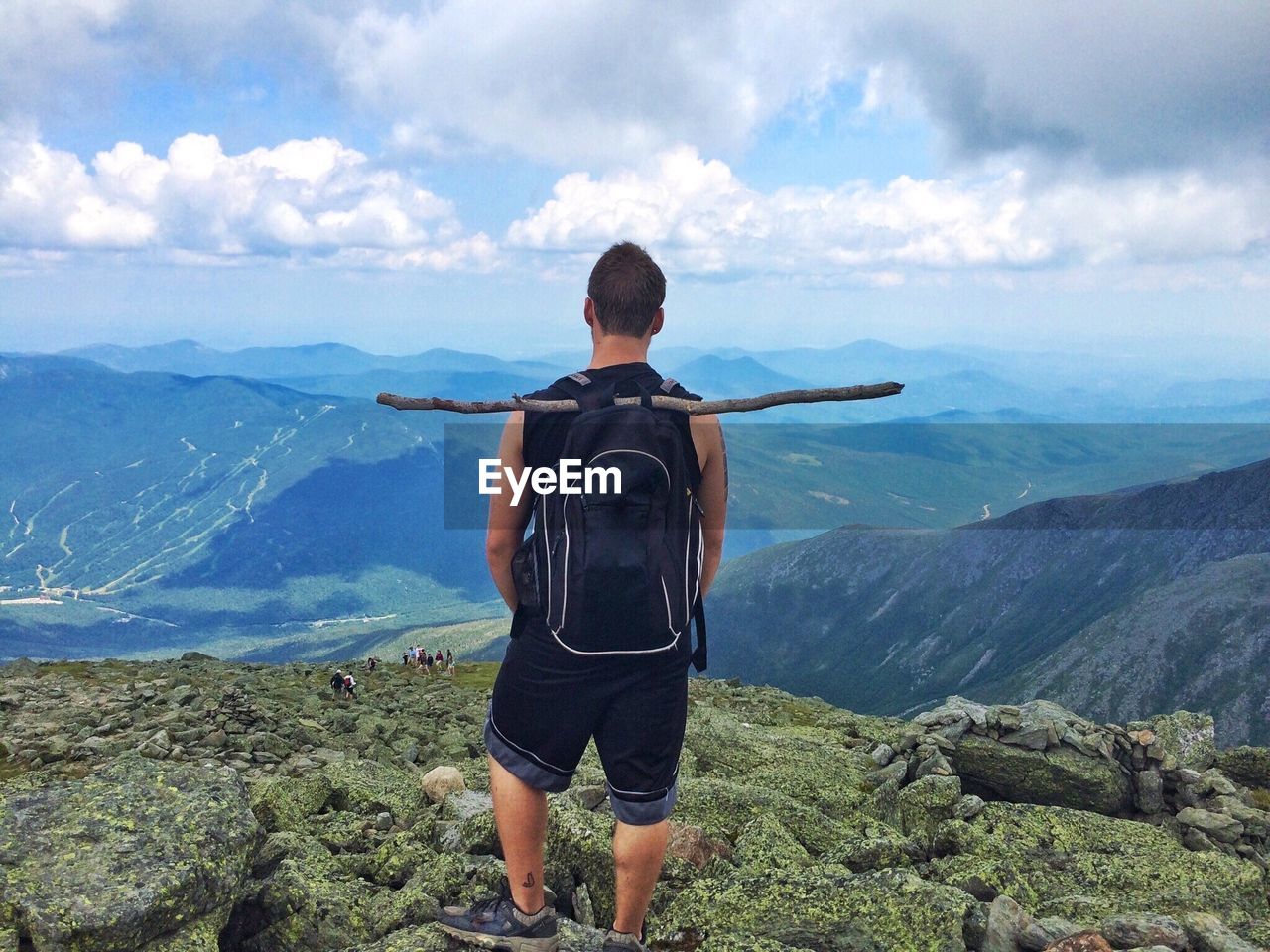 Rear view of man with backpack standing on mountain against sky