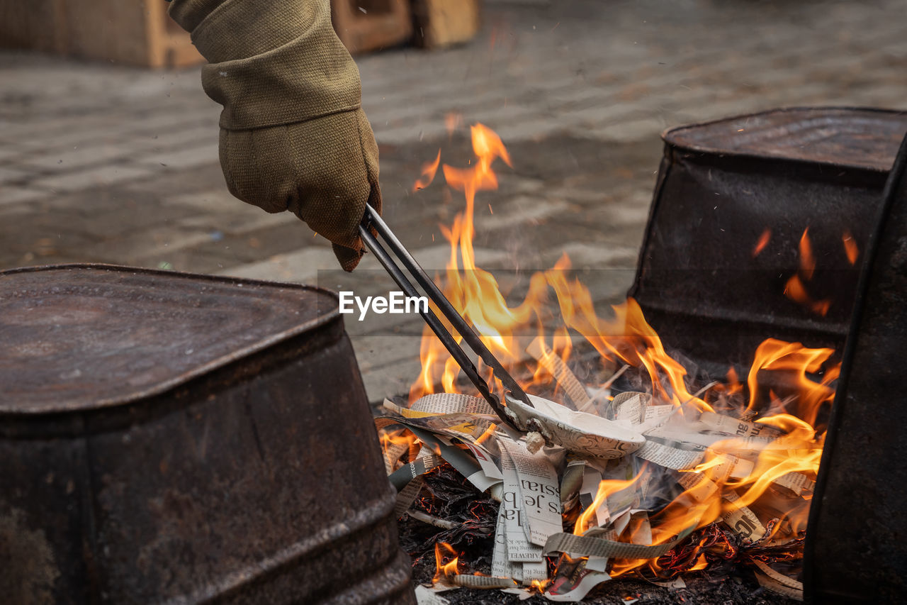 Western raku reduction bins being loaded with pottery using protective gloves and tongs into a fire