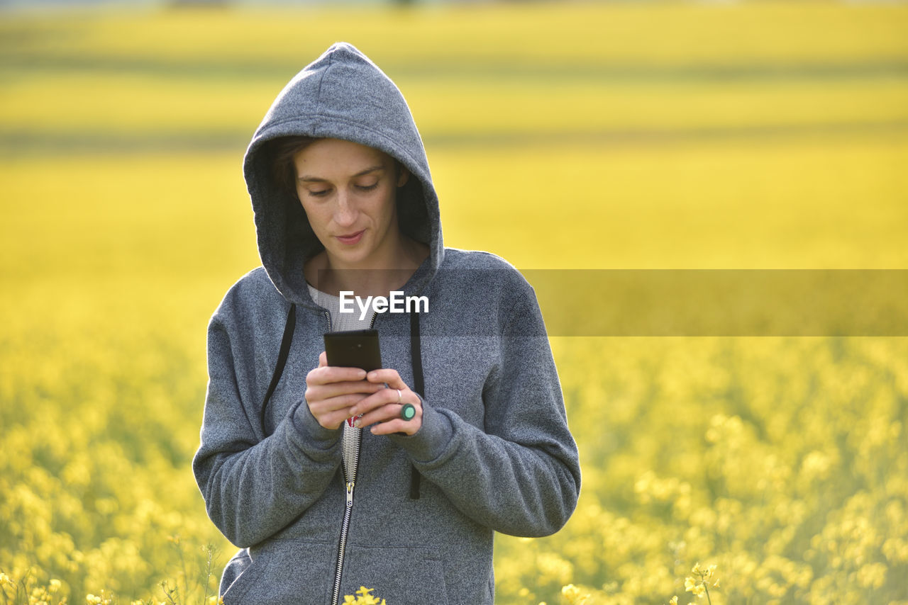 Young woman using phone on field