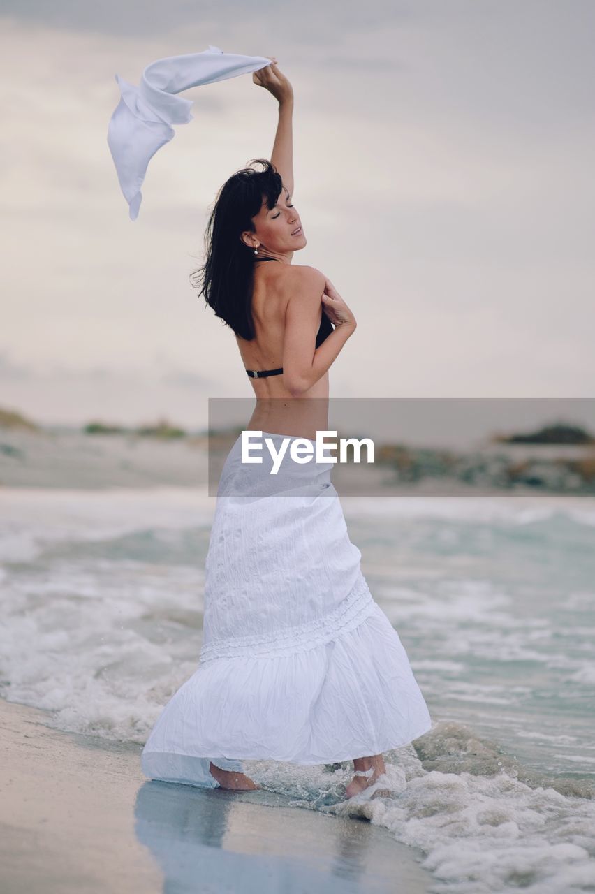 Woman with top wading in sea against sky