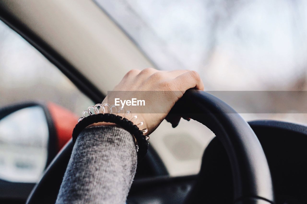 Cropped hand of woman driving car