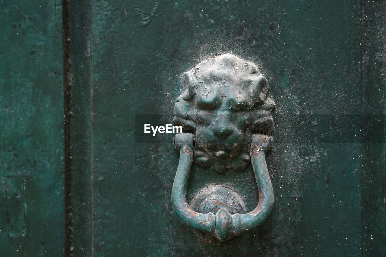 CLOSE-UP OF DOOR KNOCKER ON METAL GATE