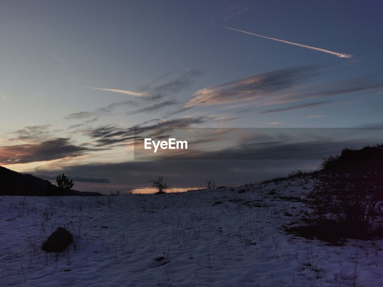SCENIC VIEW OF SNOW COVERED LAND AGAINST SKY DURING SUNSET