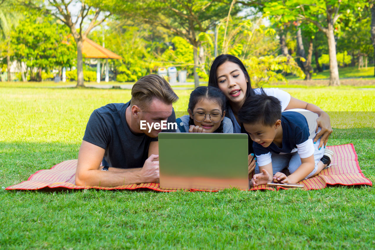 Happy family using laptop at park