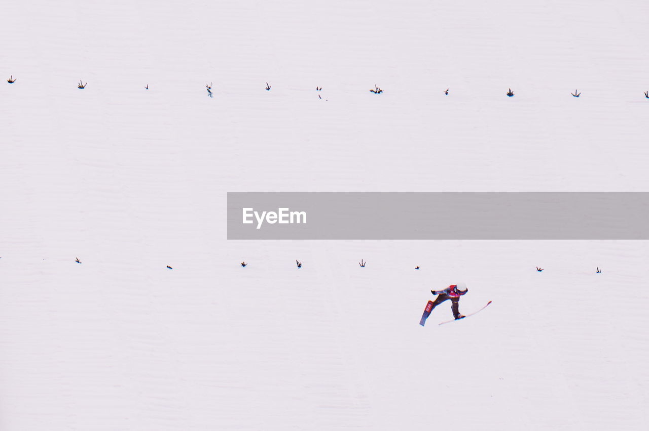 HIGH ANGLE VIEW OF PEOPLE SKIING ON SNOW