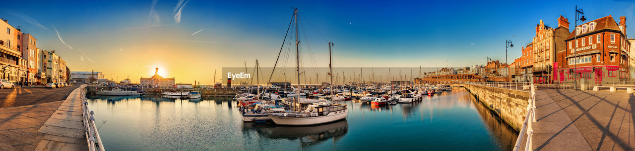 BOATS MOORED AT HARBOR AGAINST SKY DURING SUNSET