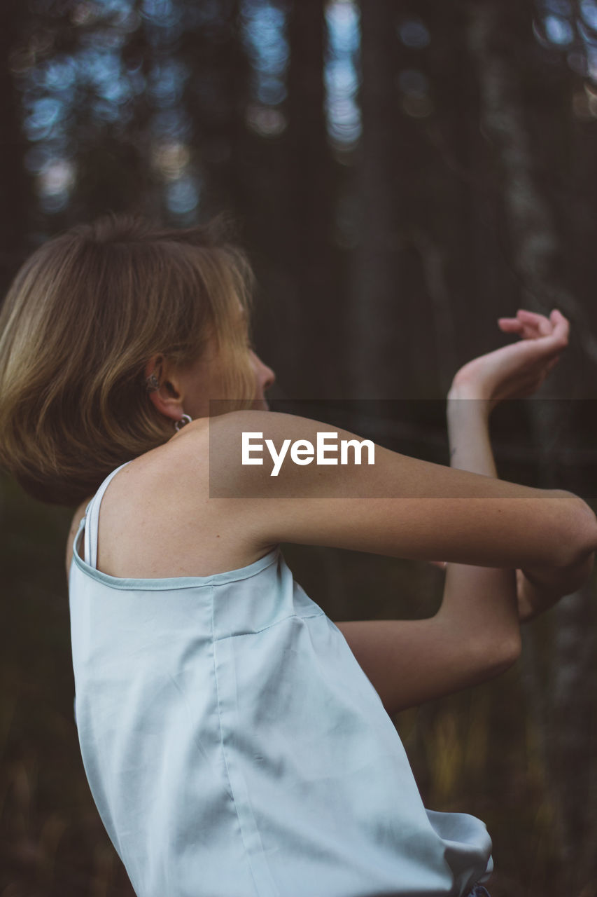 Side view of young woman dancing in forest