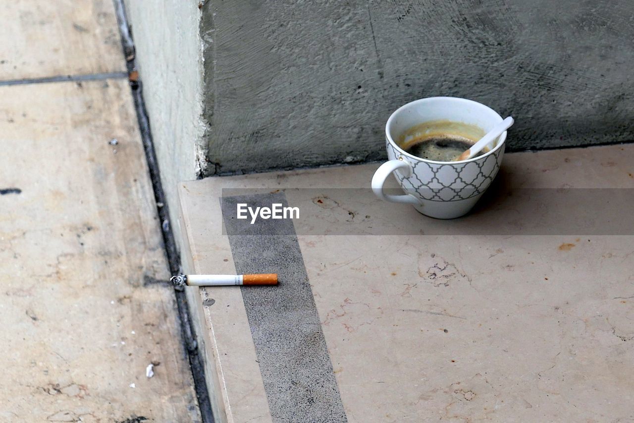 High angle view of cigarette in coffee cup outdoors