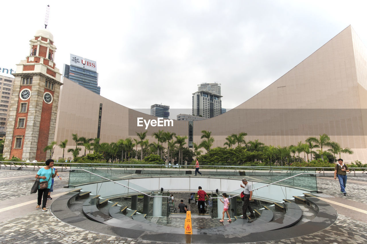 People by clock tower at tsim sha tsui by sea in city