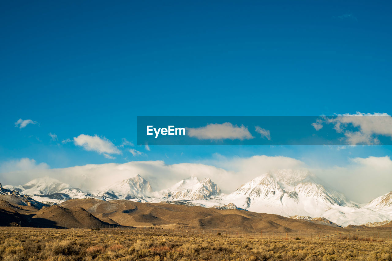 Scenic view of snowcapped mountains against blue sky