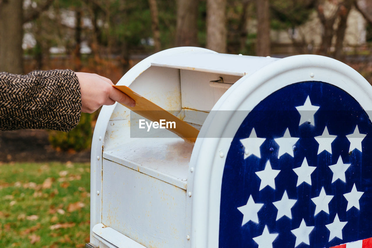 Close-up of hand putting mail in box