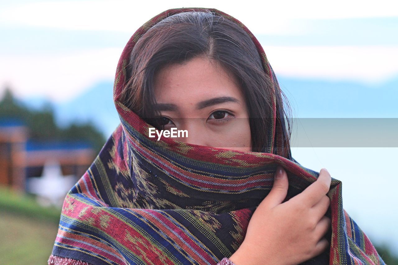 Portrait of woman covering face with shawl