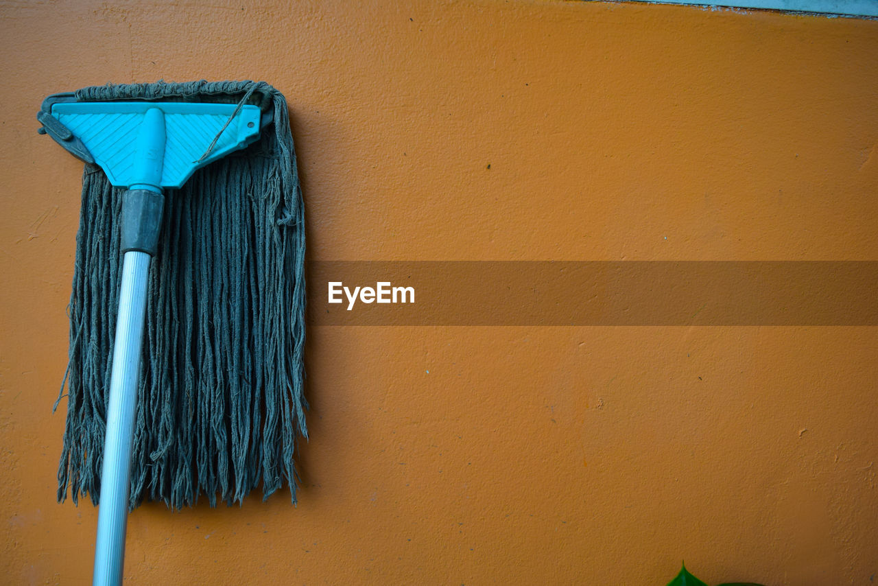 Blue mop on brown wall