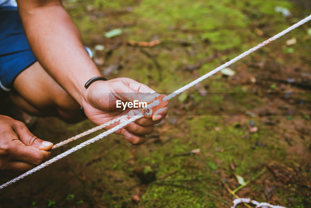 Close-up of hand holding rope with equipment