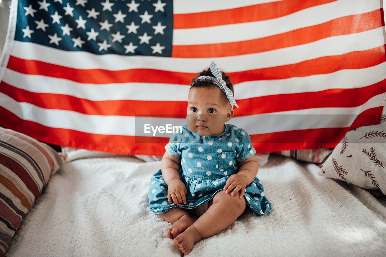 Cute girl sitting against american flag