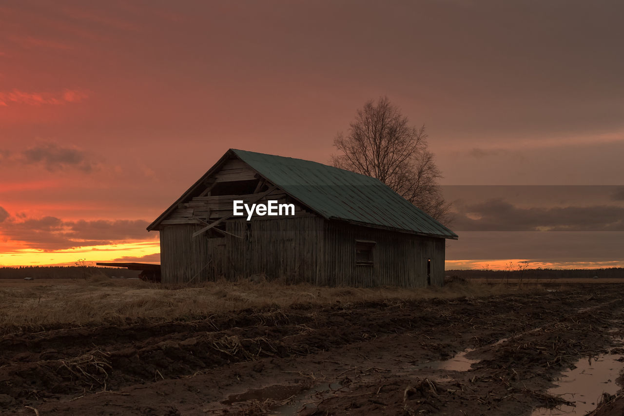 House on field against sky during sunset