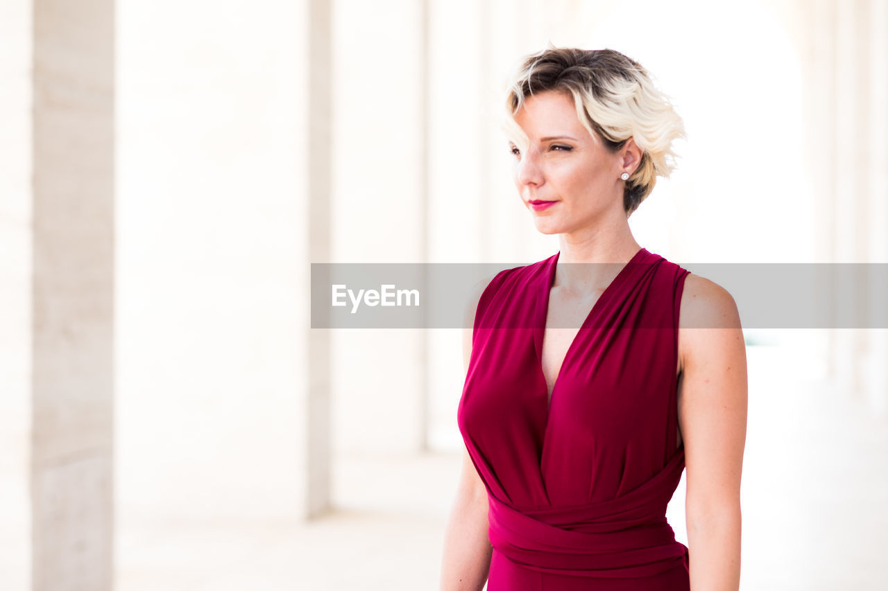 Beautiful woman looking away while wearing maroon dress