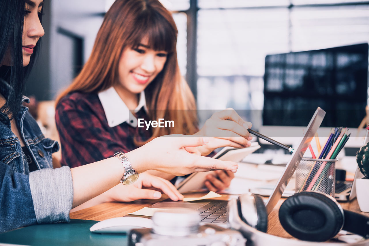 Businesswomen using laptop while working at desk in office