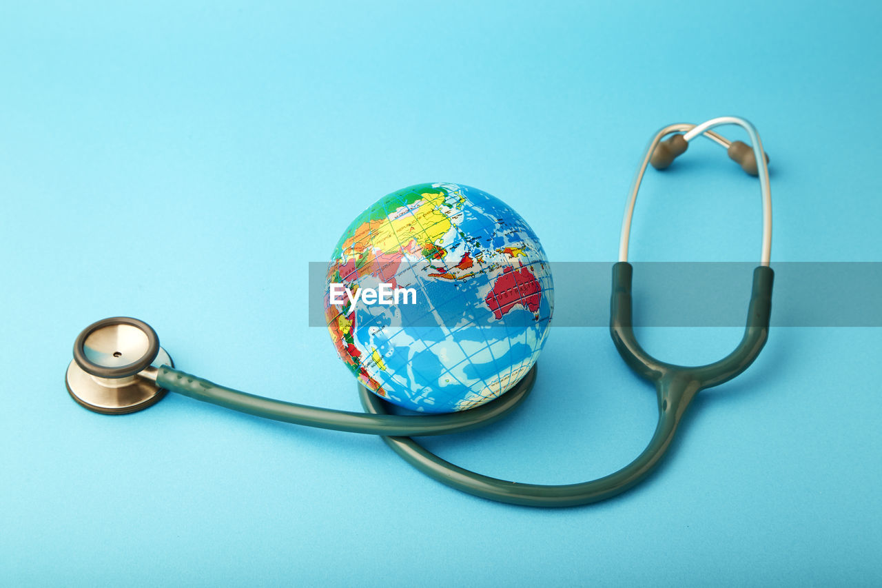 Close-up of globe with stethoscope over blue background