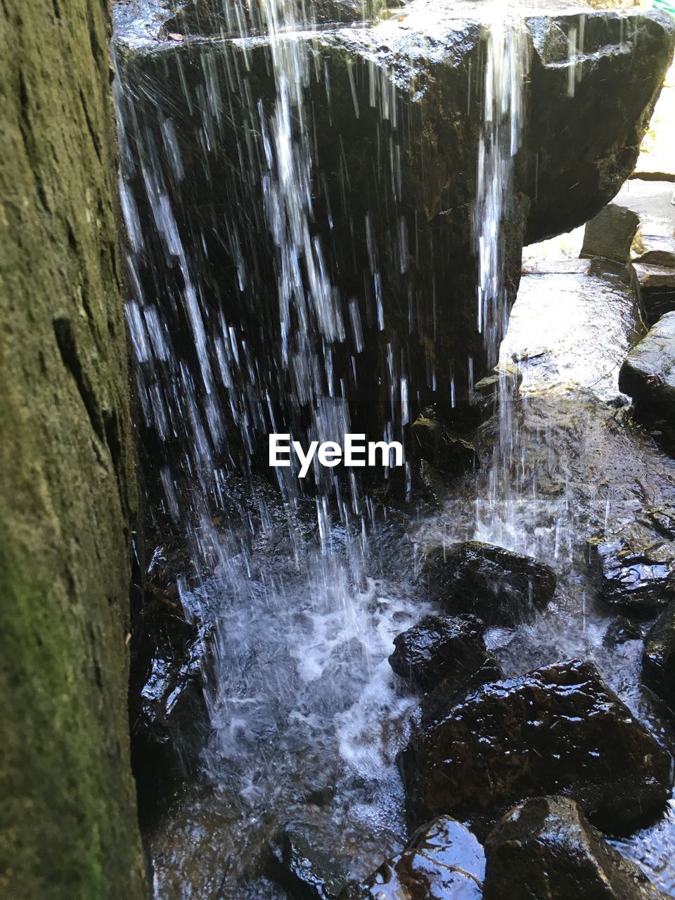 CLOSE-UP OF WATERFALL AGAINST ROCKS