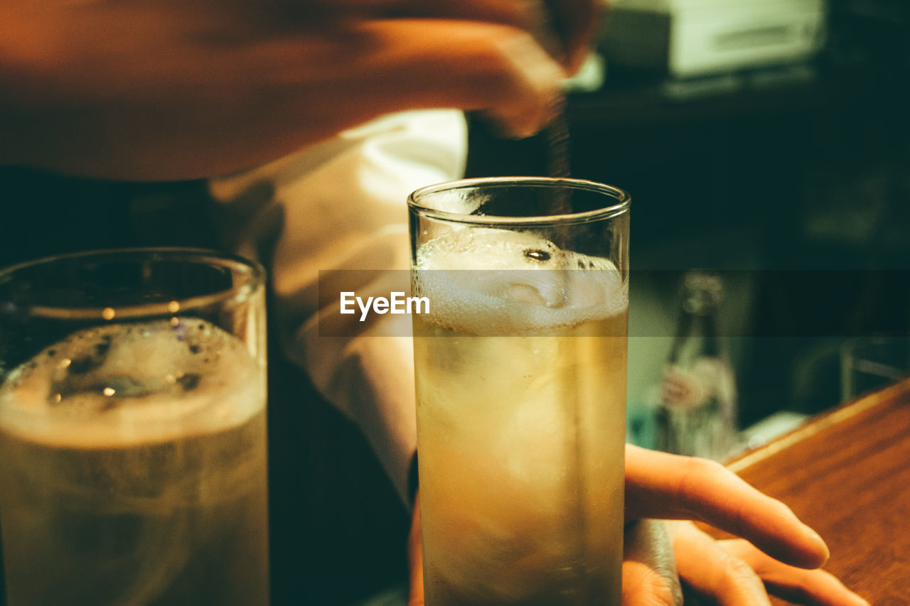 Cropped hands of bartender stirring alcohol in glass on bar counter