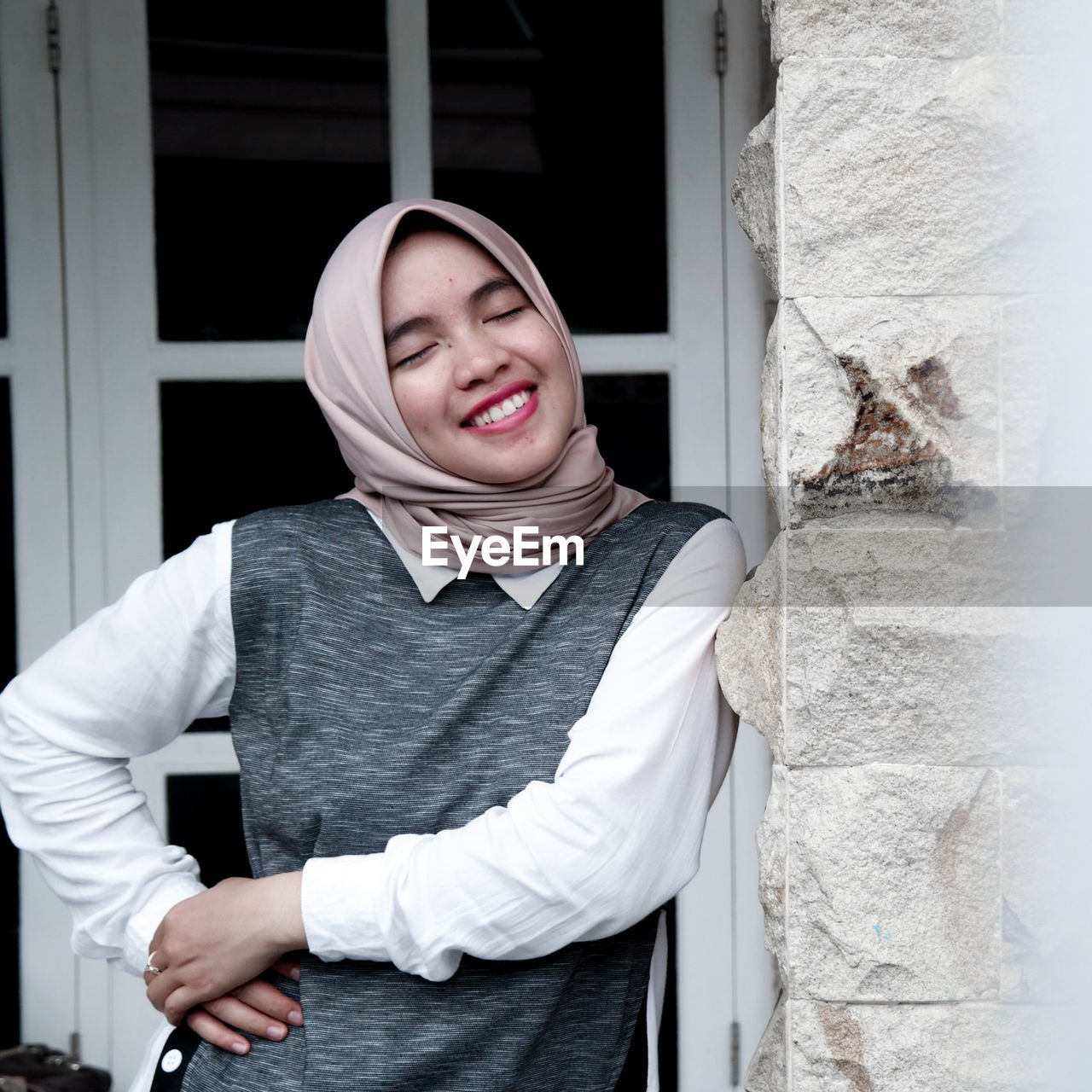 Portrait of smiling young woman standing against wall