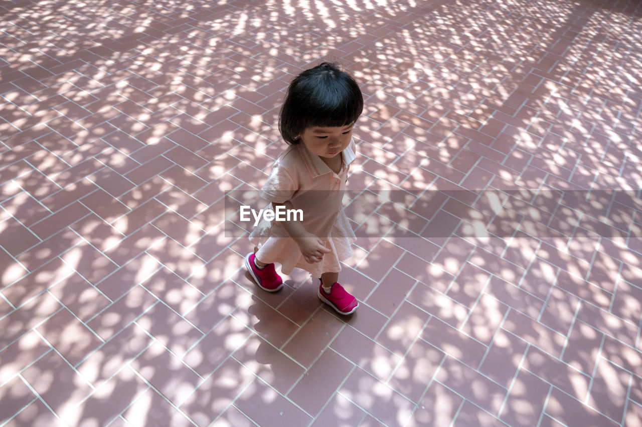 HIGH ANGLE VIEW OF CUTE GIRL ON TILED FLOOR