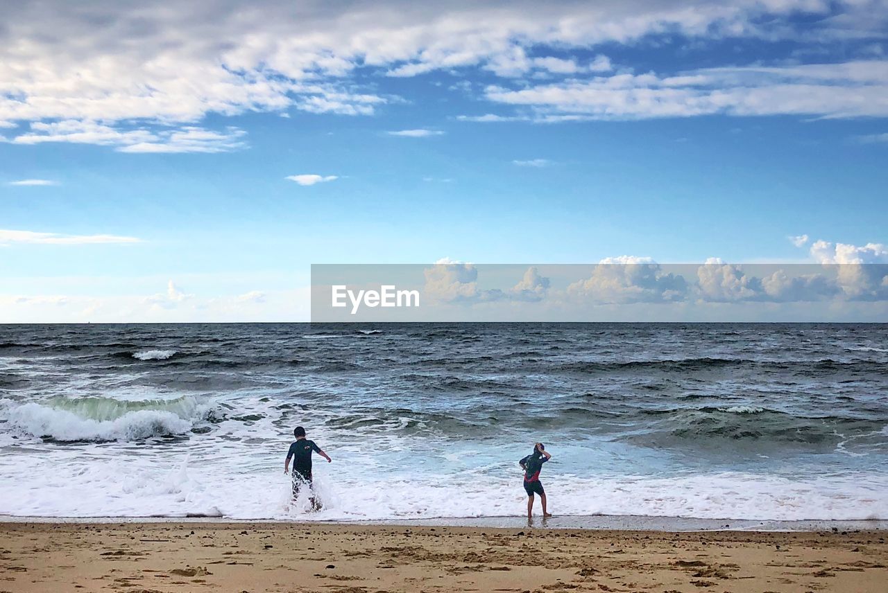 MEN ON BEACH AGAINST SKY