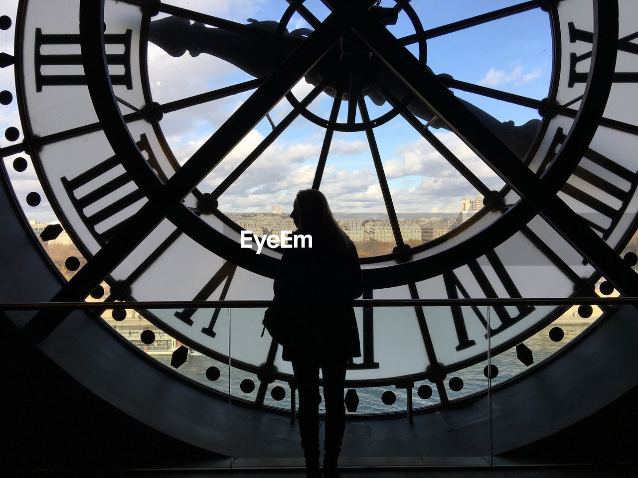 Low angle view of silhouette woman standing against clock tower