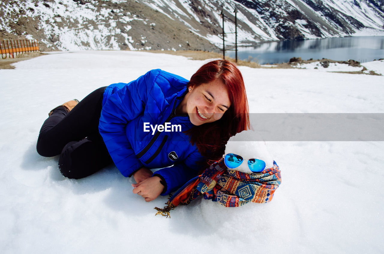 Young woman lying down on snow covered land