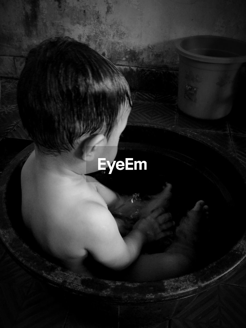 Shirtless baby boy sitting in bathtub at home