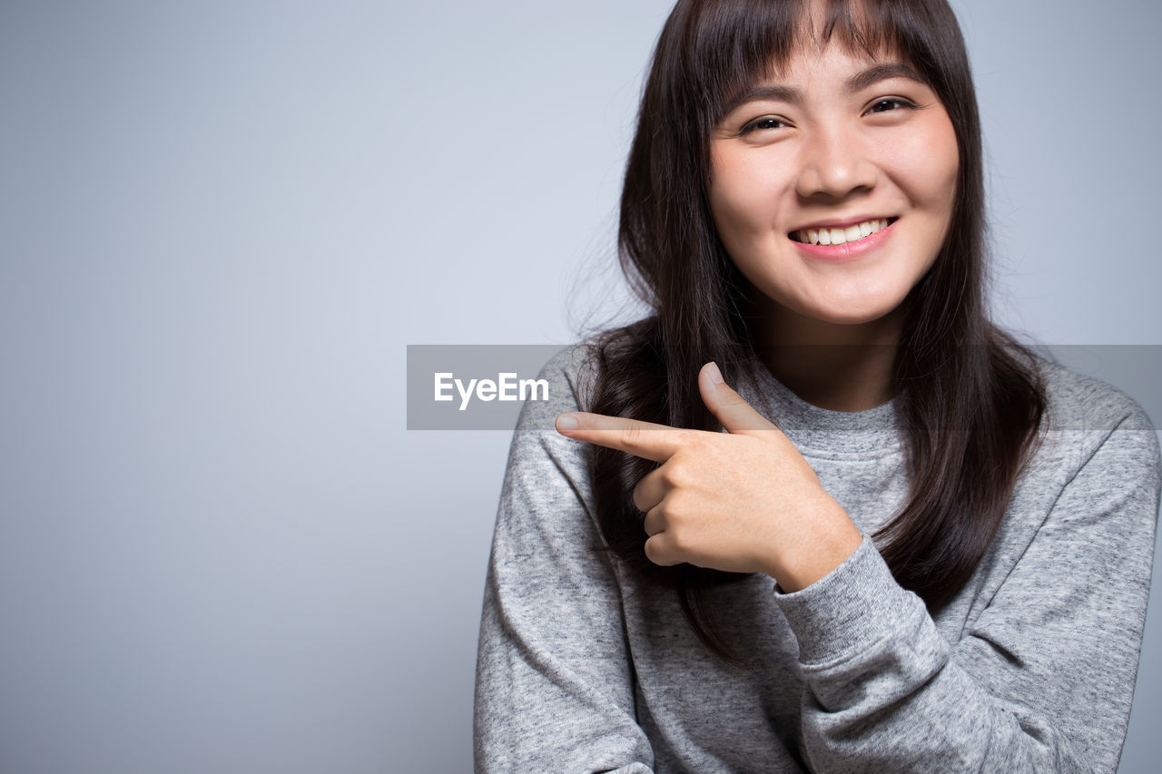 Smiling young woman against gray background