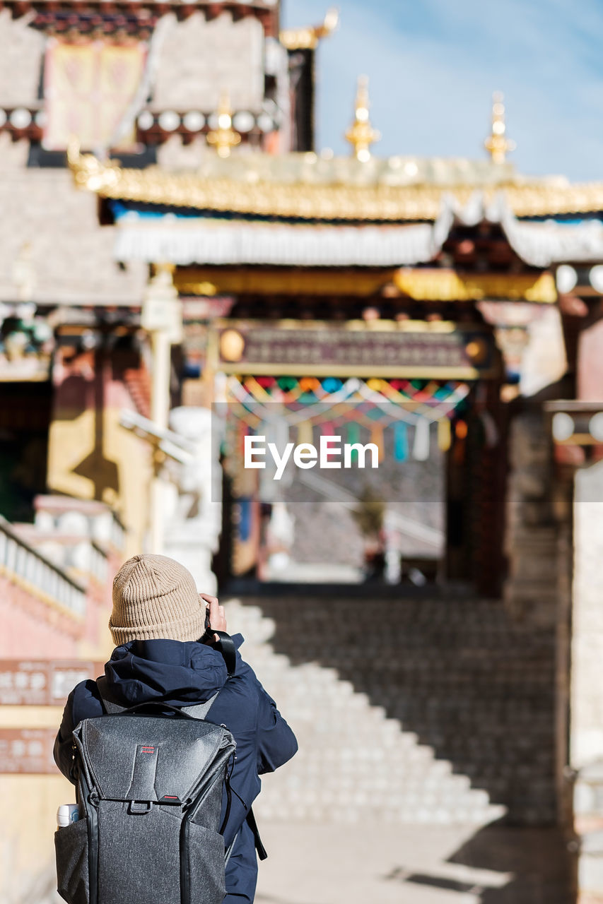 Rear view of woman with backpack standing at temple