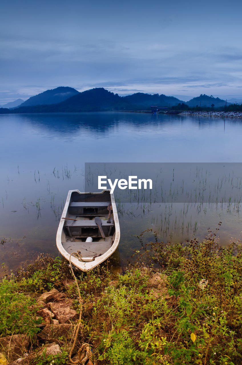 Boat on moored in lake against cloudy sky