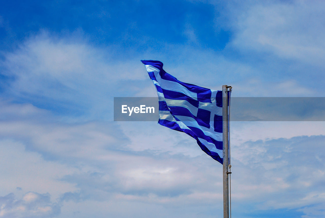 Low angle view of greek flag against blue sky