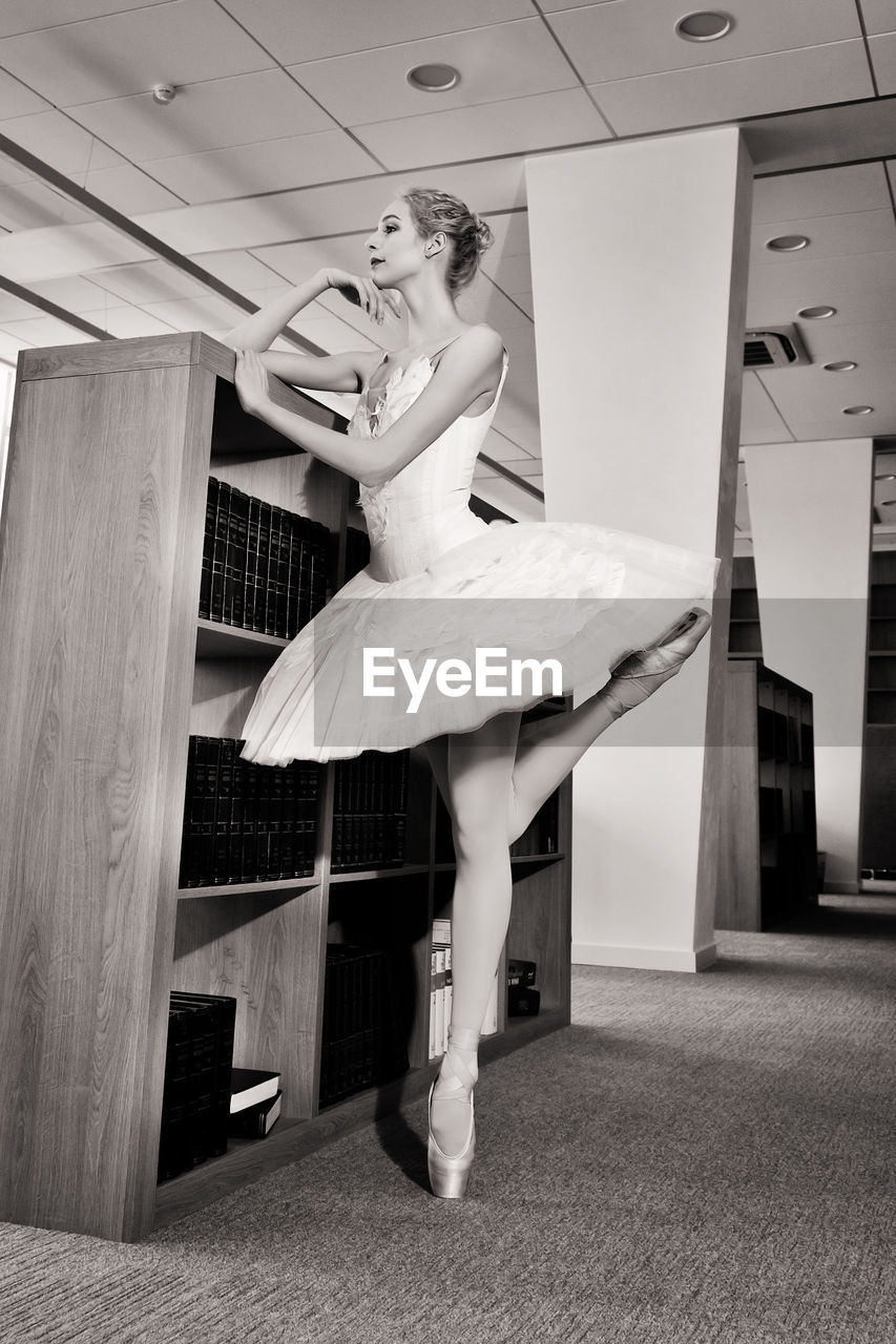 A charming ballerina went to the library to choose a new book during a break