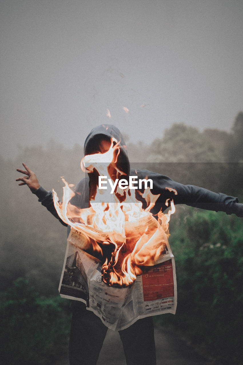 Man standing by burning newspaper