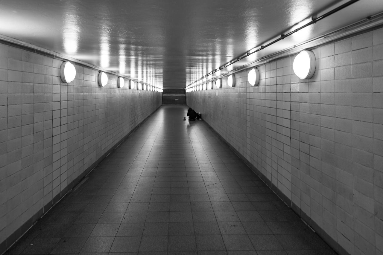 subway, black and white, architecture, illuminated, black, monochrome, monochrome photography, lighting equipment, tunnel, indoors, public transportation, wall - building feature, transportation, line, tile, the way forward, subway station, light, built structure, infrastructure, white, flooring, darkness, ceiling, snapshot, one person, electric light, diminishing perspective, underpass, underground walkway, walking, metro station, full length, footpath, city, tiled floor, rear view, fluorescent light, corridor, public transport, arcade, wall, lifestyles, city life, adult