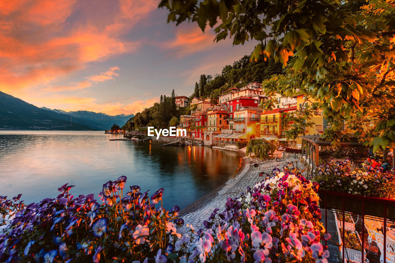 Village of varenna on lake como at sunset with illuminated houses and colorful flowers