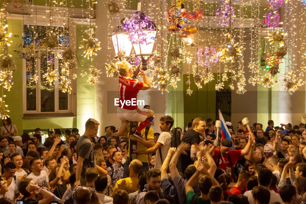 GROUP OF PEOPLE AT ILLUMINATED CHRISTMAS DECORATIONS