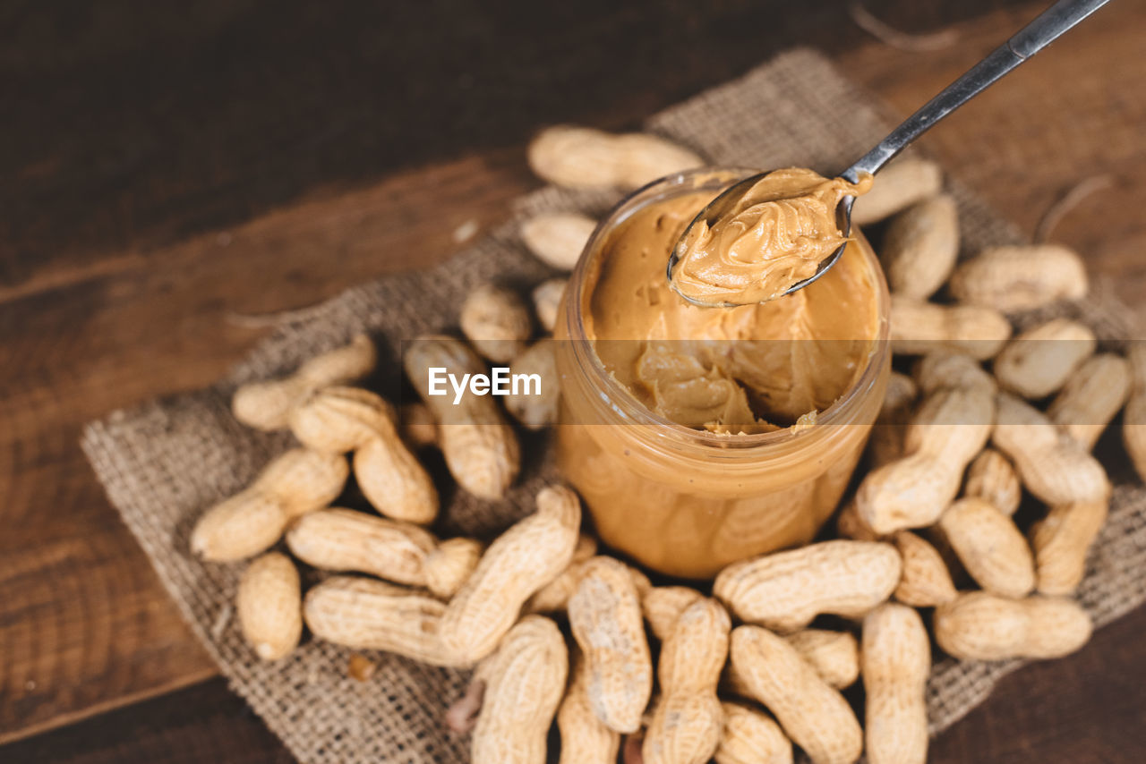 High angle view of peanut butter in container on table with groundnut