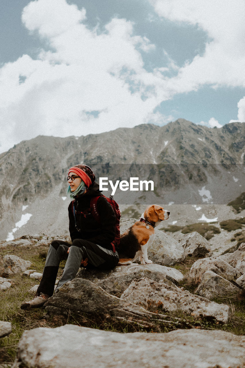 Girl sitting on rock against mountains with her beagle dog