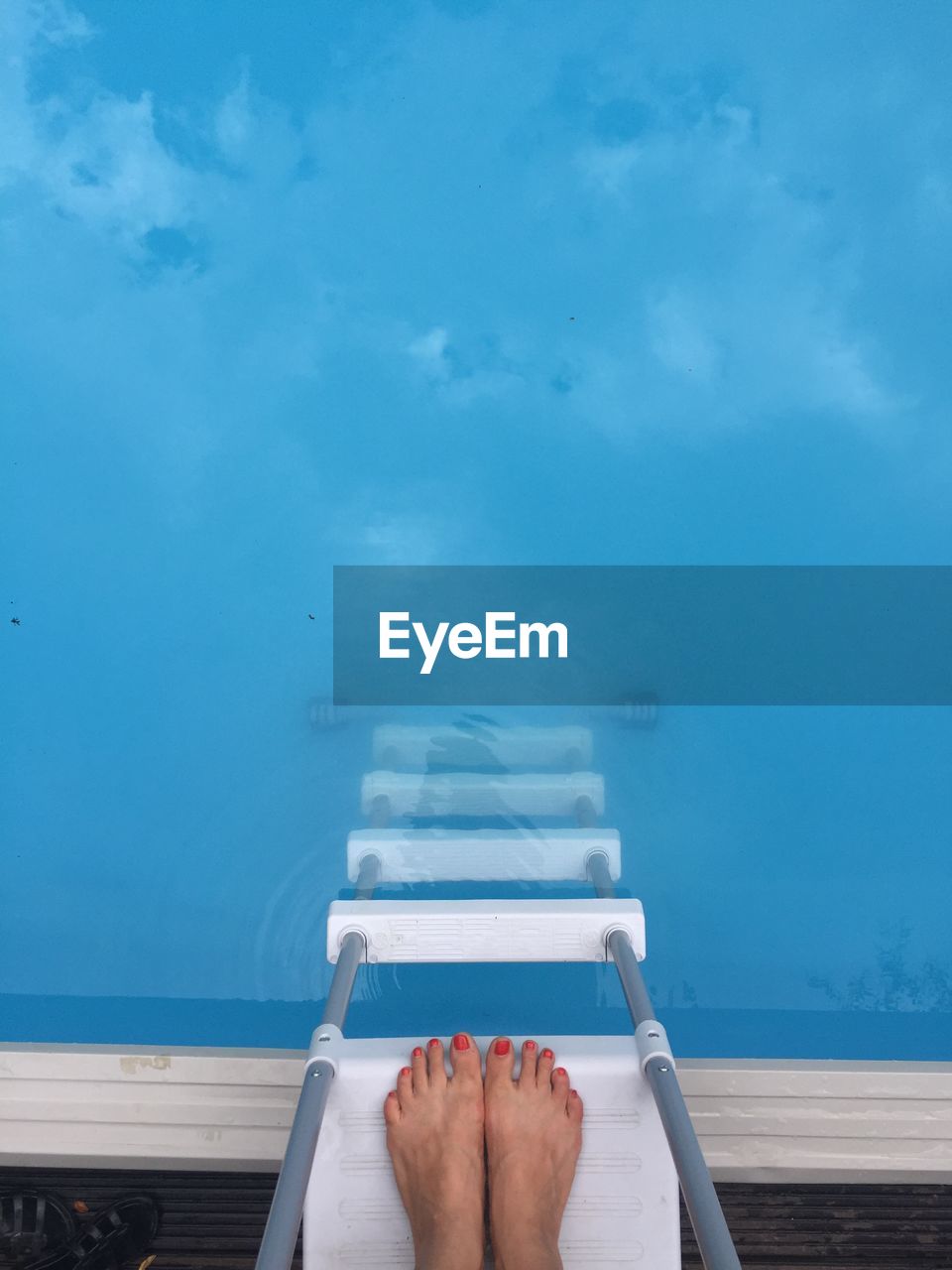 Low section of woman on ladder at poolside