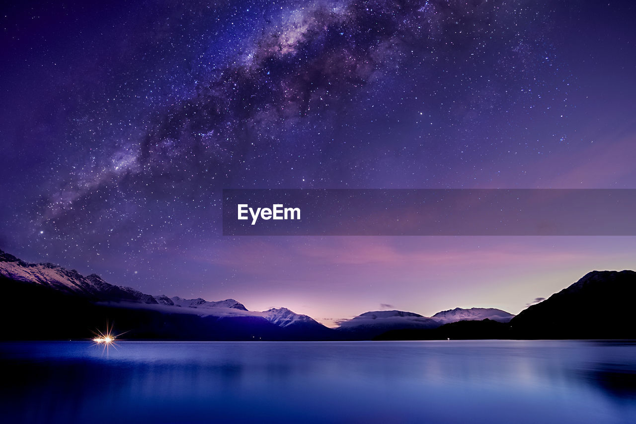 Scenic view of lake and mountains against sky at night