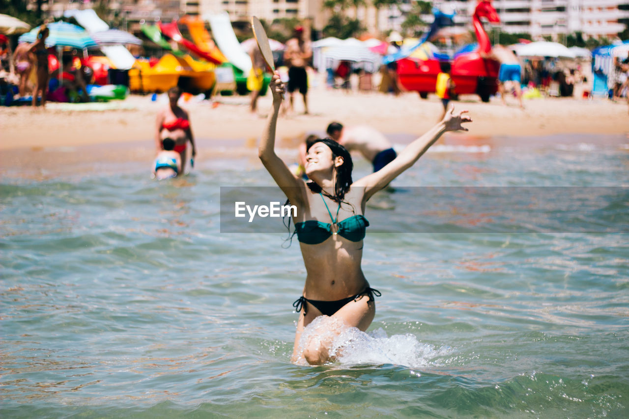 Happy young bikini woman playing in sea